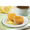 Two lemon cupcakes on a plate with a cup of coffee and lemon slices in the background.